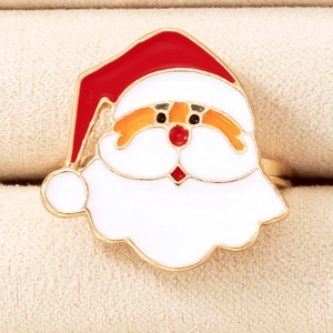 Macro shot of festive enamel Santa Claus ring with red and gold details on beige surface