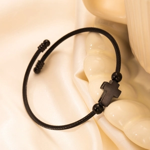 Minimalist black twisted wire steel bracelet with cross pendant on silk fabric