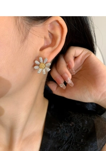 Close-up of model wearing daisy flower stud earrings with sparkling crystals and silver petals