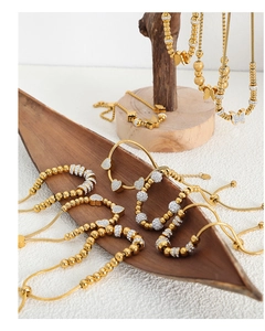 Détail de bracelets dorés avec breloques papillon et cœur en zircons sur un plateau