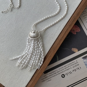 Detailed view of pearl tassel pendant necklace with silver metal cap and adjustable clasp