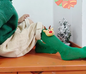 Detail der grünen Weihnachts-Wadenstrümpfe für Kinder mit 3D-Plüsch-Rentier-Puppe