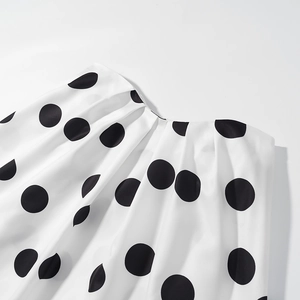 Gros plan sur le satin blanc à pois noirs avec détails plissés de l'encolure