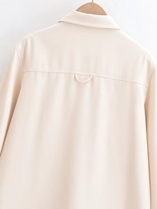Detailaufnahme der Rückseite des cremefarbenen Langarmshirts am Kleiderbügel mit Ledertextur