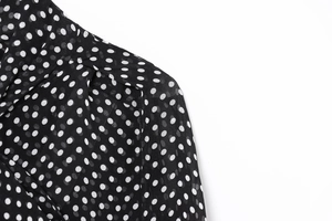 Close-up of lightweight black chiffon fabric with white polka dot pattern and collar detail