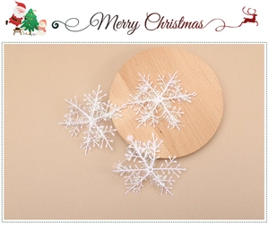 Close-up of white snowflake Christmas ornaments on a wooden tray with warm pink background