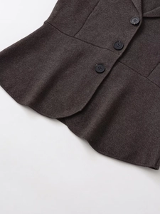 Gros plan sur le tissu en maille anthracite épais avec trois boutons noir mat du gilet