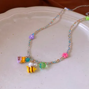 Colorful beaded necklace set with honey jar and bee charms on ceramic plate