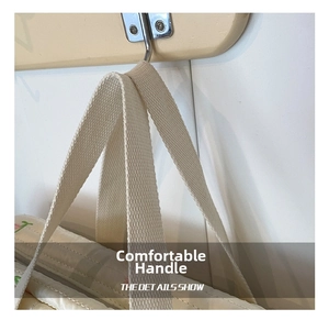 Detail shot of the thick woven handles on the cream-white diaper bag showing durable texture