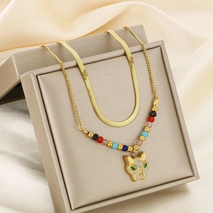 Detail of gold double-layer snake chain necklace with leopard head pendant and beads