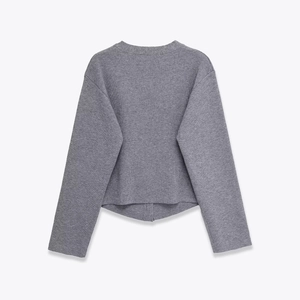 Detail view of the back of a grey long-sleeved knitted jacket with soft button texture
