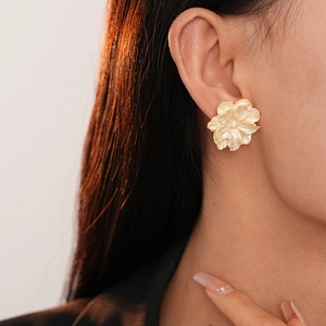 Gros plan de boucles d'oreilles fleurs en acrylique blanc crème avec éclat de perle