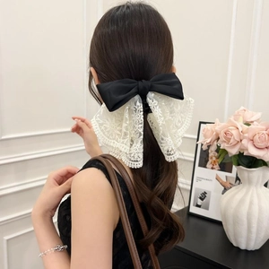 Elegant large black satin bow with white lace embroidery shown on a model ponytail