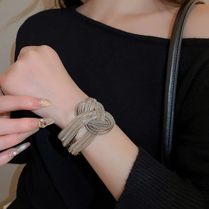 Detailed close-up of multilayer silver braided metal cuff bracelet with center knot design