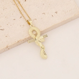 Detail of an 18K gold plated Ankh pendant with intricate snake wrap on a beige stone