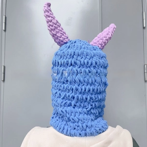 Close-up of sky blue crochet balaclava with purple devil horns and thick knit texture