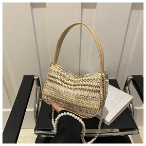 Détail d'un sac en paille avec broderie papillon rose et bandoulière en perles