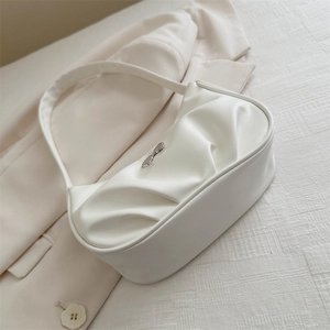 Minimalist white pleated underarm bag with silver logo on beige blazer background