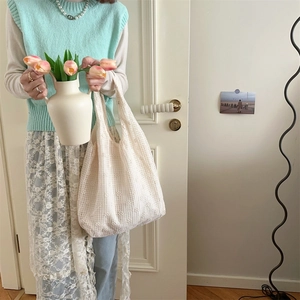 Detailed texture of off-white lace crochet tote bag held by a model in a natural setting