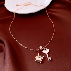 Rose gold necklace with zircon camera and key pendants on red silk fabric background