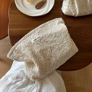 Close-up of beige crochet lace makeup bag with simple wish label on wooden table