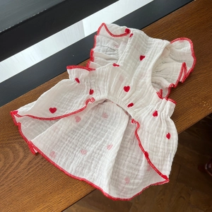 Detailed texture of white pet dress with red heart print and ruffled edges on wood