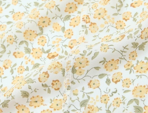 Détail macro du tissu floral jaune montrant la couture surjetée et la texture fine