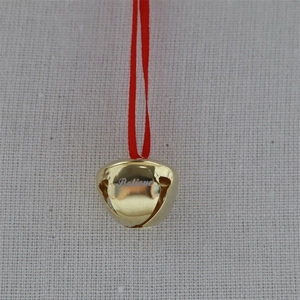 Golden Christmas bell pendant with red ribbon and Believe engraving on textile surface
