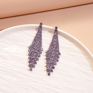 Close-up of elegant purple rhinestone tassel earrings on a textured white plate
