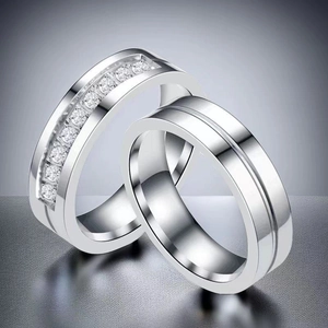 Detailed view of silver stainless steel couple rings with cubic zirconia inlay and engraving