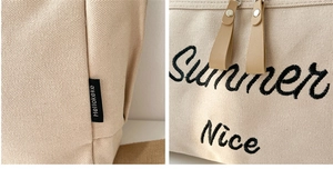 Detailed macro view of beige canvas tote bag with Hellokeke label and Summer embroidery