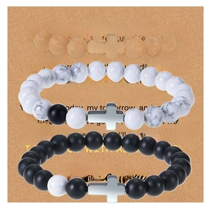 Detailed view of couple beaded bracelets with silver crosses on a brown gift card