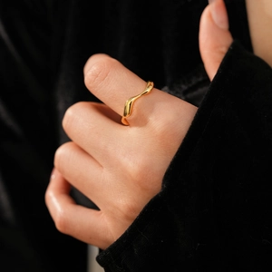 Macro view of 18k gold plated irregular wavy ring showing polished mirror surface on finger
