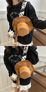 Brown suede cowboy hat bag with cow print strap and plush cow pendant detail
