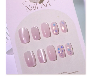 Macro shot of 10 piece nude pink cat-eye press-on nails with blue glitter on display card