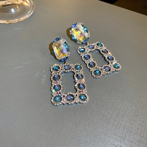 Detailed close-up of emerald-green rectangular crystals and blue gemstone tassels on earrings