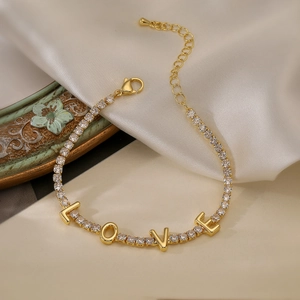 Detailed shot of gold bracelet with LOVE letters and zircon stones on silk background