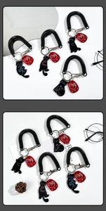 Close-up of black cat acrylic spring keychain with red CAT tag on white background