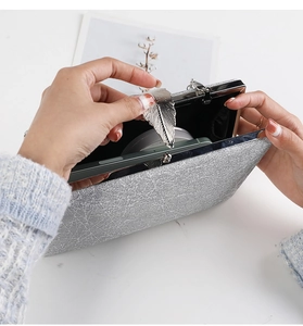 Detail of silver textured clutch bag with leaf metal clasp showing internal phone storage