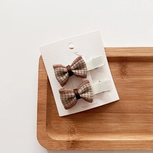 Detail of plaid fabric bow hair clips with brown checkered pattern on a display card