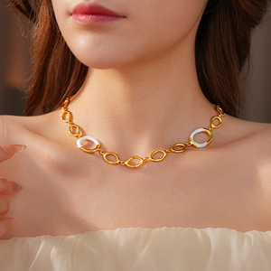 Detail of a gold chain necklace with white enamel rings worn by a model