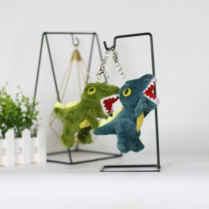 Detail of green and teal plush dinosaur keychains hanging on a metal display stand