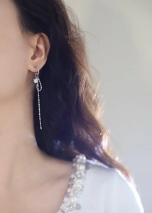 Detail of silver bow tassel earrings with sparkling rhinestones worn by a model