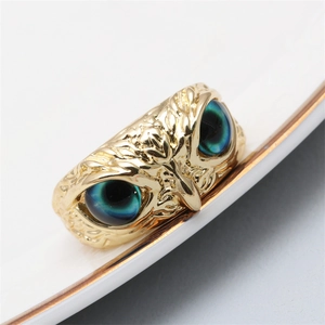 Macro shot of owl ring featuring turquoise cat-eye stone eyes and golden finish detail