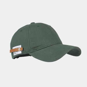 Close-up of deep green canvas baseball cap with vintage patch and metal rivet detail