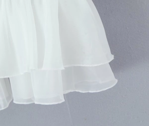 Dettaglio dell'orlo in chiffon bianco a strati con cuciture sottili sulla camicetta