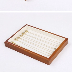 Detailed view of wood jewelry tray with white velvet lining and gold necklaces