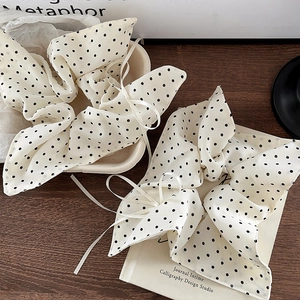Elegant cream polka dot scrunchie set with white silk ribbons on a wooden background