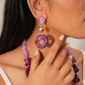 Close-up of purple marble texture resin earrings with golden spherical metal accents