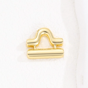 Detailed macro view of a glossy gold Libra zodiac pendant with a polished mirror finish